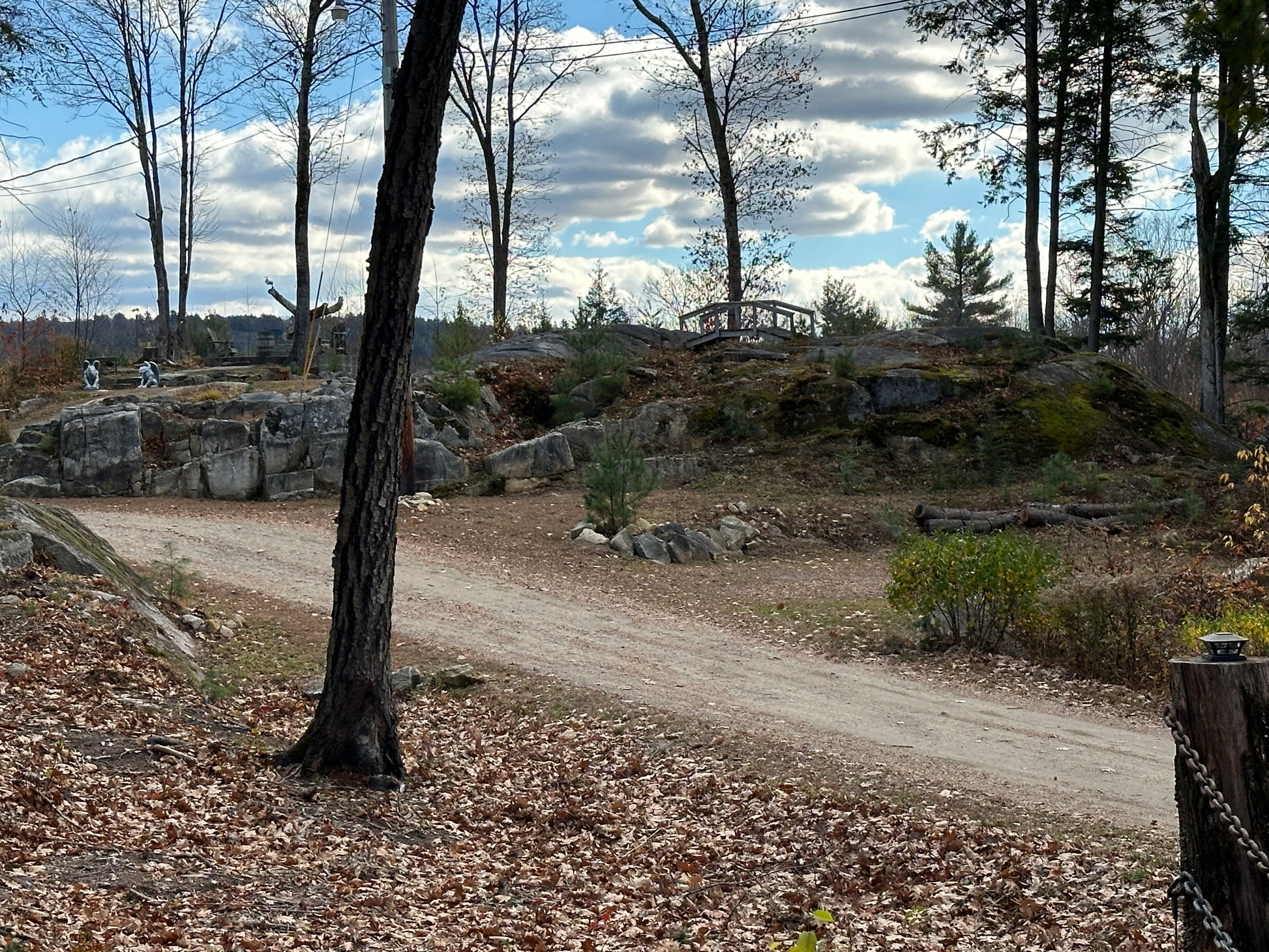 Scenic view of a ledges and outcroppings and  forested area with a dirt path, trees, and rocky landscape. Nature View NH Estate