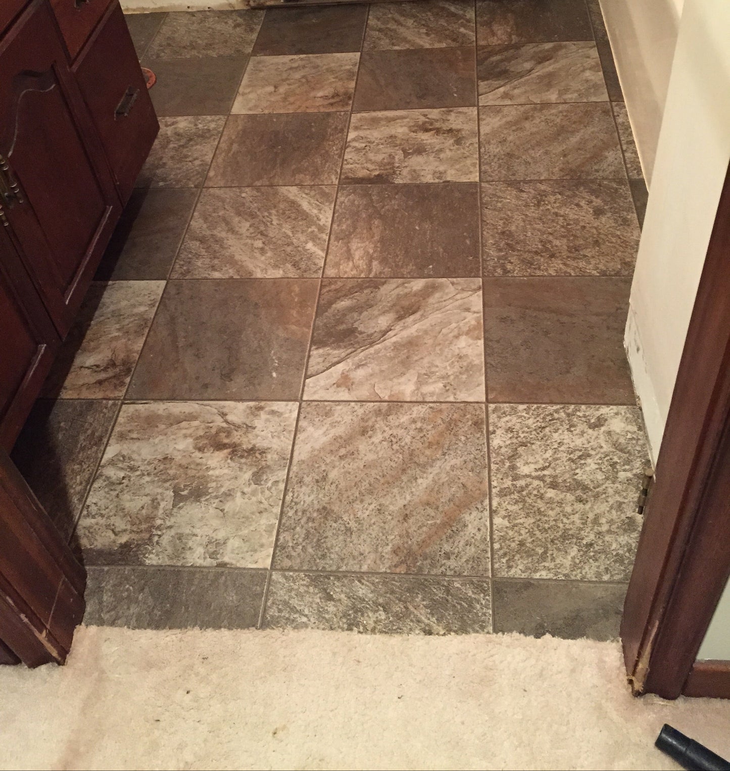 Tile wall with a wooden  mahogany cabinet in a bathroom setting