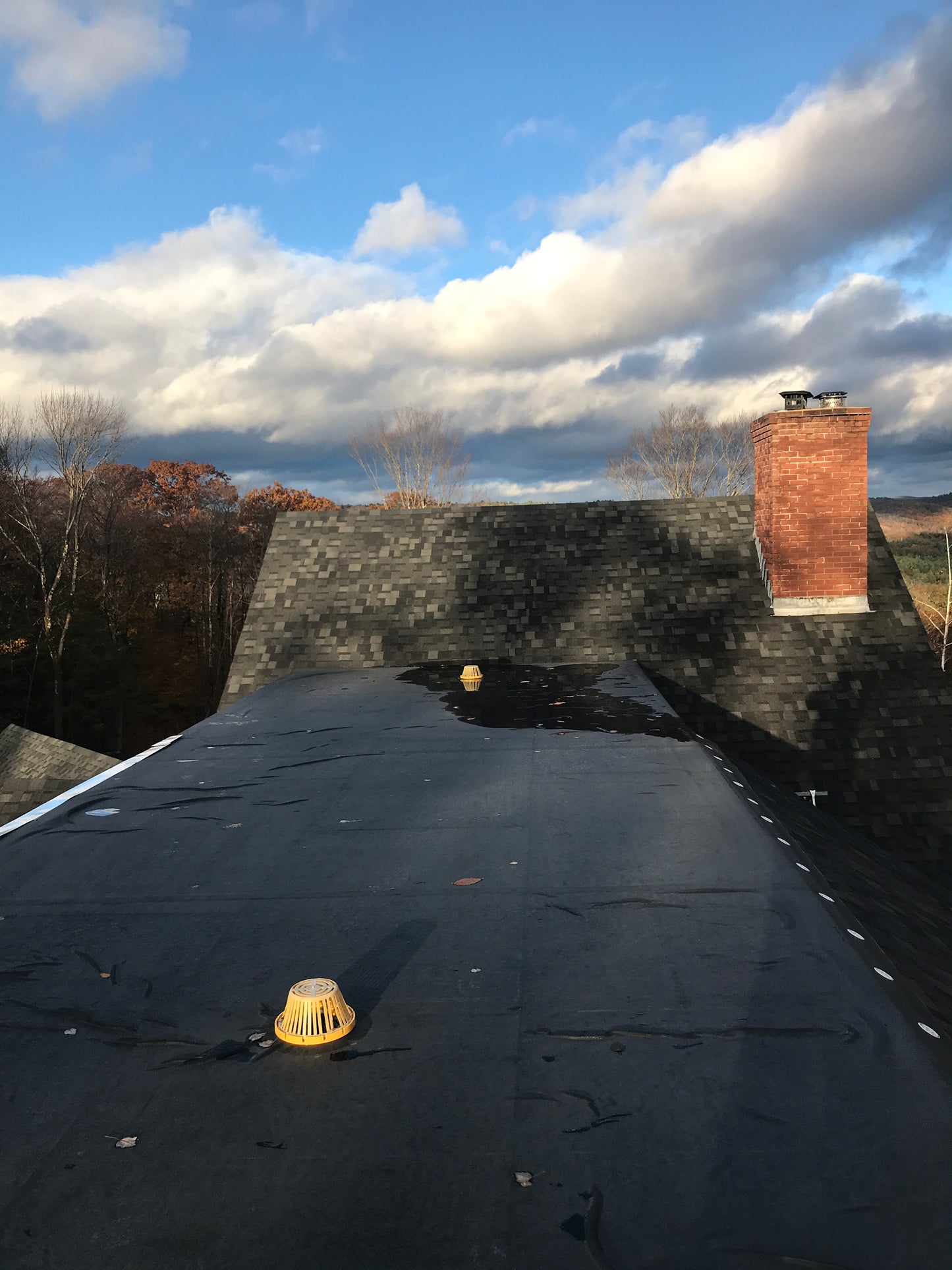 roof with a reflective surface showing a blue sky and clouds.