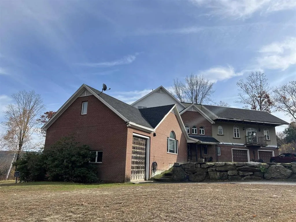 4-story brick and Stucco house with  new roofing a 3 car garage beautiful house under a blue sky.