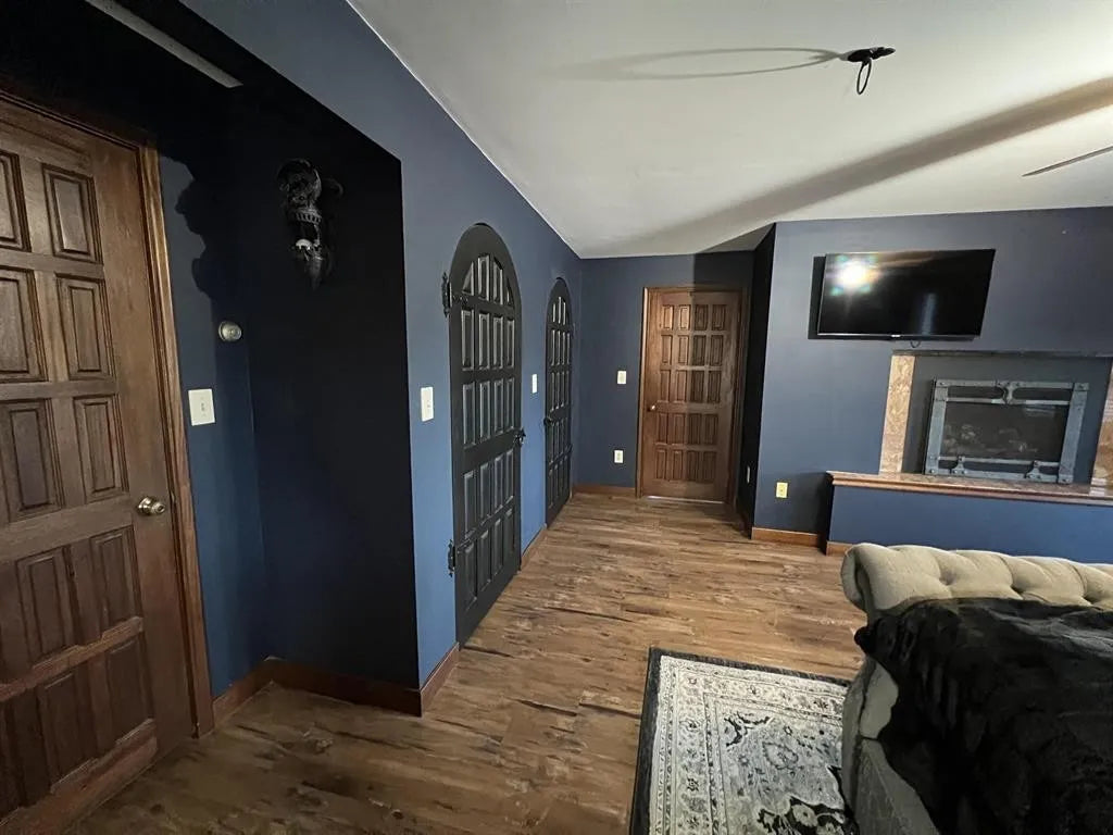 Living room with blue walls, wooden floors, and a fireplace.