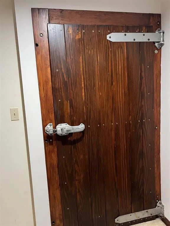 Wine cellar door with metal hardware on a white wall