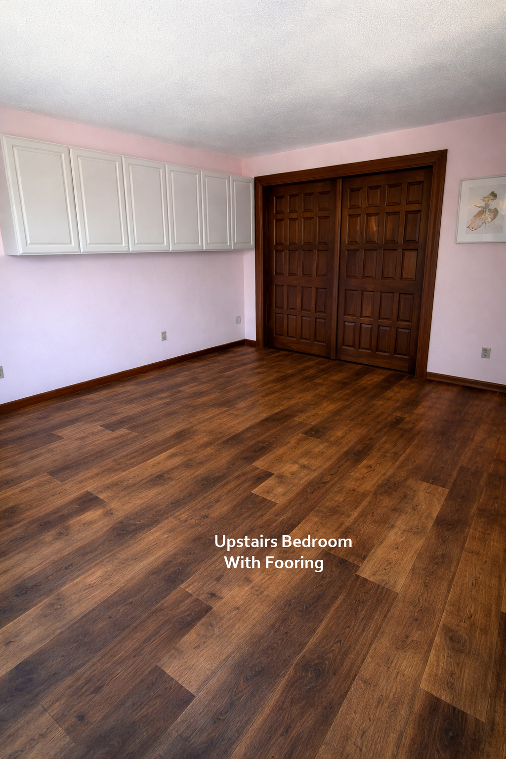 Upstairs bedroom with wooden flooring and pink walls.