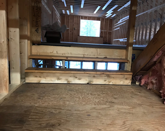 Wooden ceiling with insulation and a small window in a room under construction.